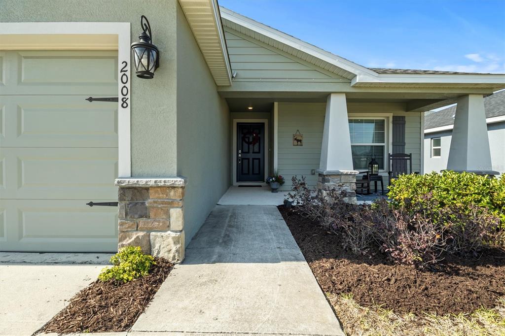 The exterior of a house features a garage, a stone-accented porch, and a walkway — 2008 NOBLE DRIVE, DAVENPORT, FL