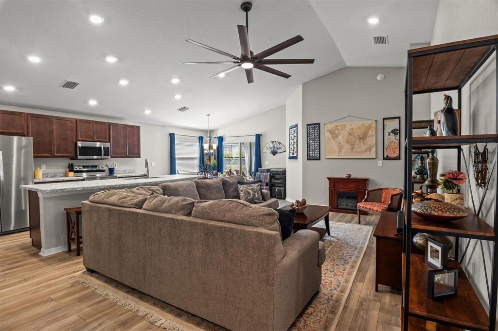 An open-concept living room and kitchen featuring a large sectional sofa and wood-look flooring — 2008 NOBLE DRIVE, DAVENPORT, FL