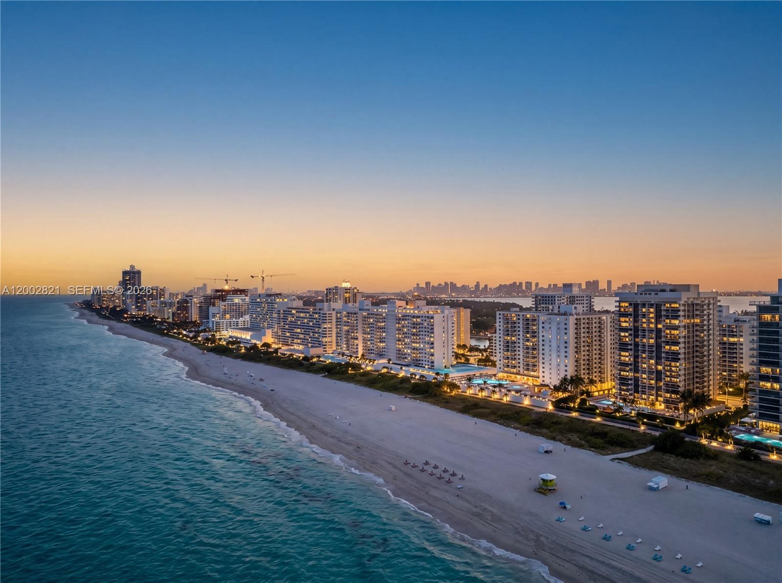 An aerial view of a sandy beach lined with high-rise buildings at sunset — 5757 Collins Ave # 1104, Miami Beach FL 33140, MIAMI BEACH, FL