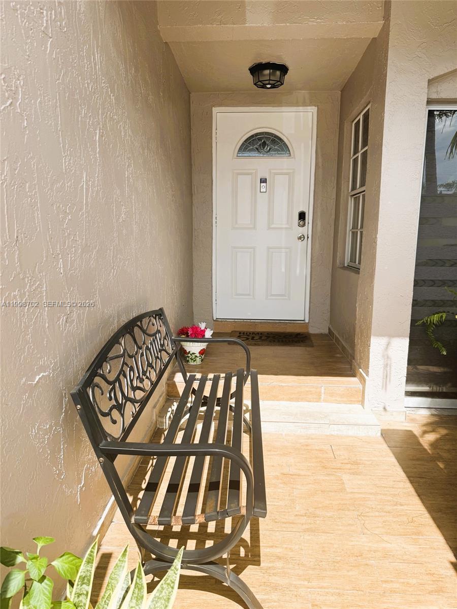 A metal bench sits on a tiled porch in front of a white front door — 6217 SW 128th Pl, Miami FL 33183, MIAMI, FL
