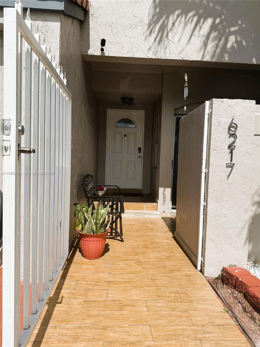 A tiled walkway leads to a white front door behind a metal gate — 6217 SW 128th Pl, Miami FL 33183, MIAMI, FL