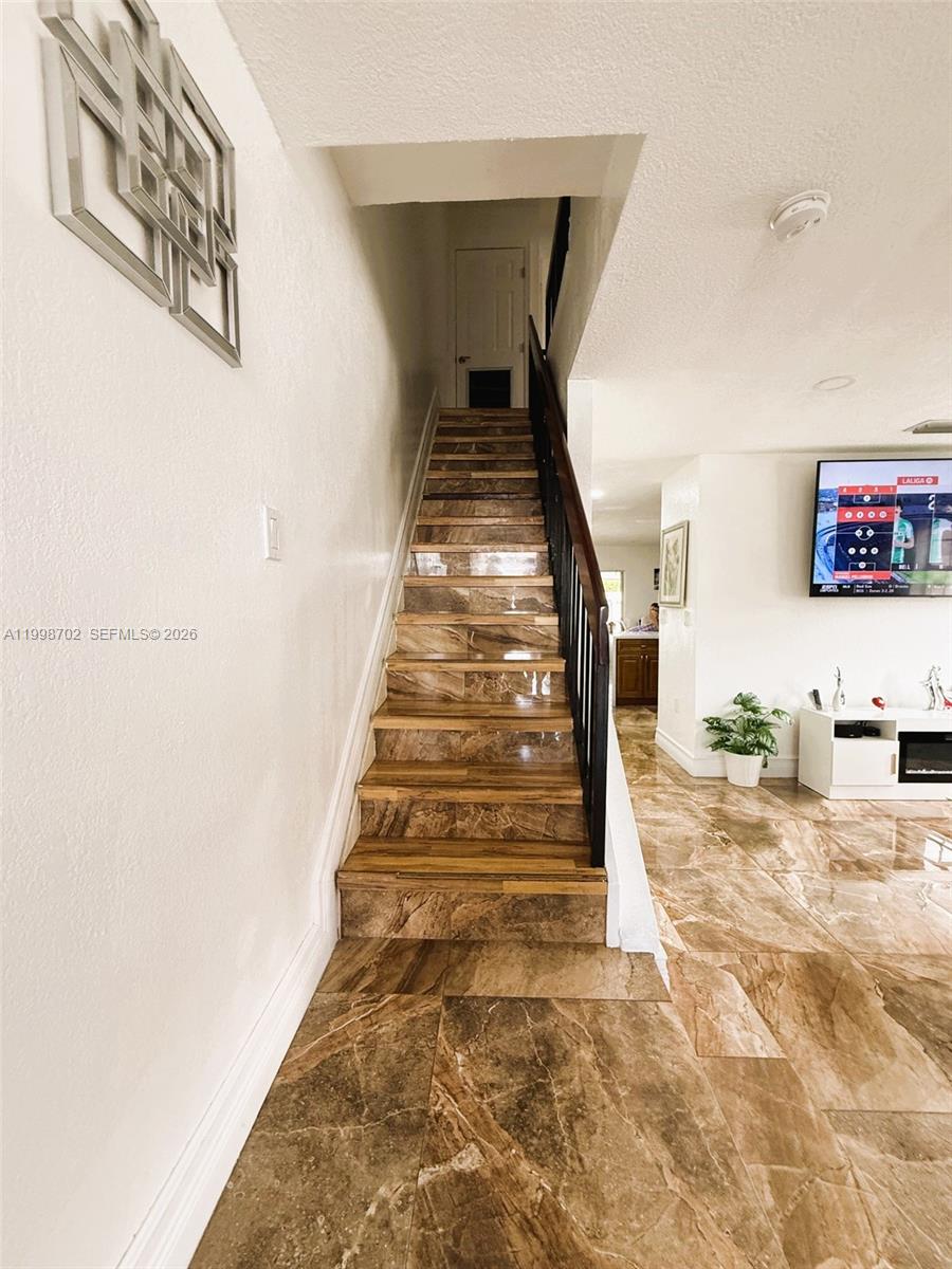 A staircase with brown marble-look tile steps leads to an upper level — 6217 SW 128th Pl, Miami FL 33183, MIAMI, FL