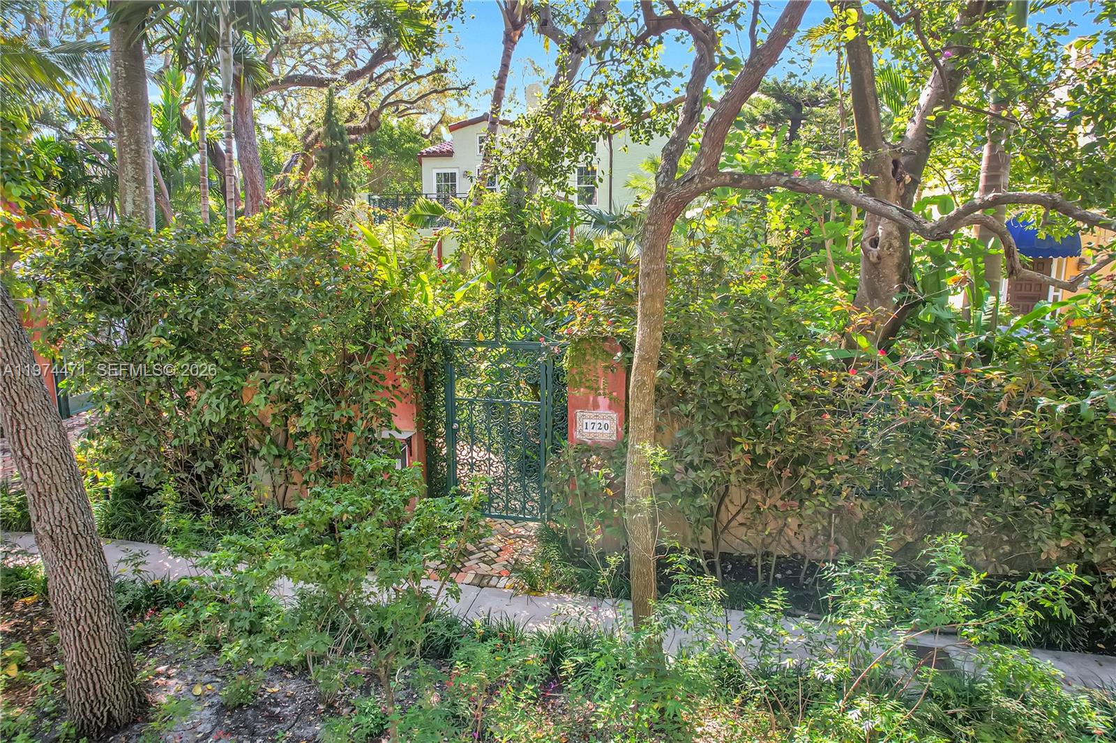 A multi-story house with a light green exterior is partially obscured by trees and foliage — 1720 Espanola Dr, Miami FL 33133, MIAMI, FL