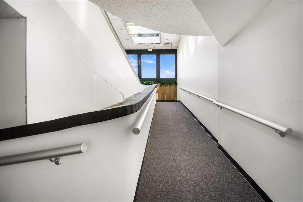 A carpeted hallway features white walls, metal handrails, and a windowed ceiling — 3390 KORI ROAD, JACKSONVILLE, FL