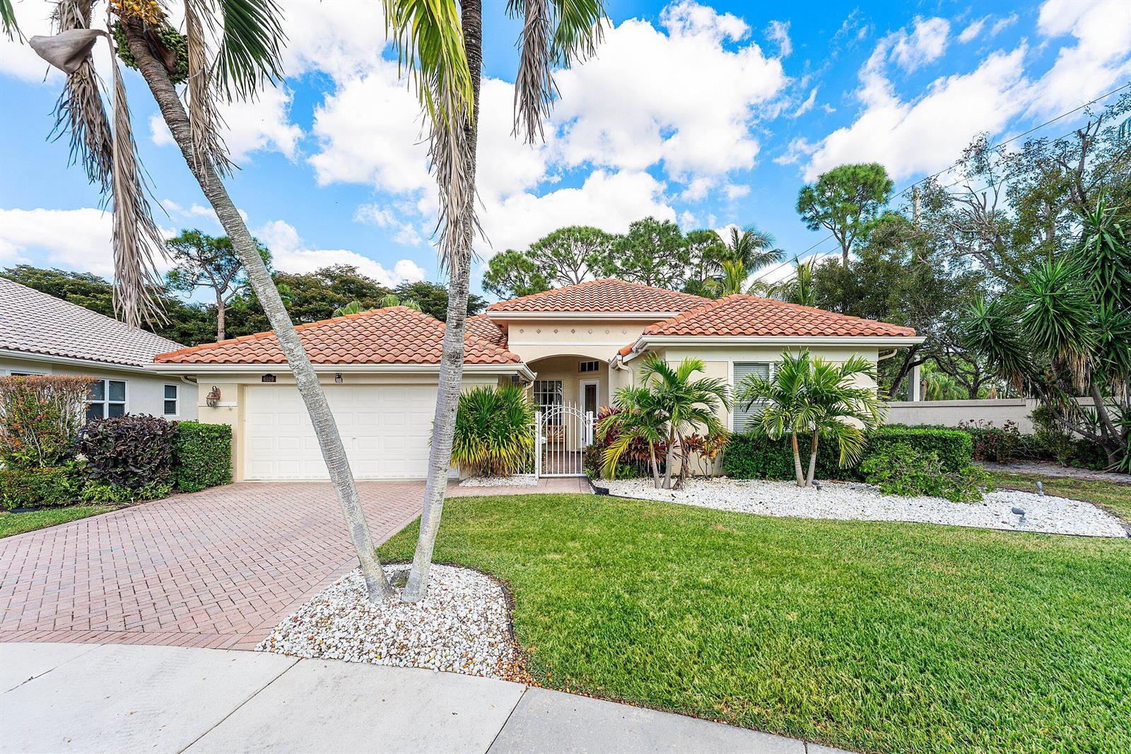 A single-story house with a tile roof, two-car garage, and palm trees in the front yard — 6529 Jog Estates Lane, Boynton Beach FL 33437, BOYNTON BEACH, FL