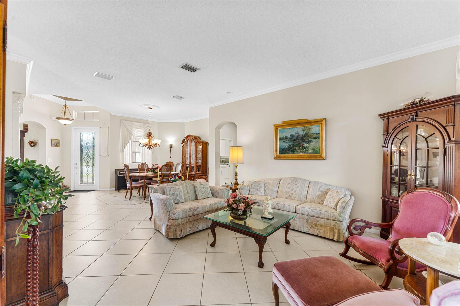A living room with tile floors, floral sofas, a glass coffee table, and dining area — 6529 Jog Estates Lane, Boynton Beach FL 33437, BOYNTON BEACH, FL