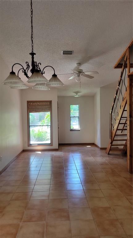A room with tiled floors, a chandelier, a ceiling fan, and a wooden staircase — 1011 LOVE LANE UNIT 31, APOPKA, FL