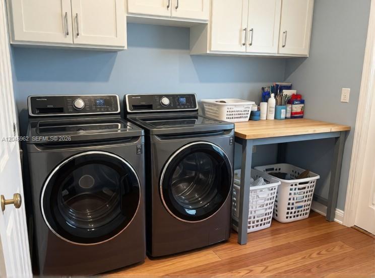 A laundry room features dark gray appliances, white upper cabinets, and a wooden folding table — 1750 W 46th St # 0, Hialeah FL 33012, HIALEAH, FL