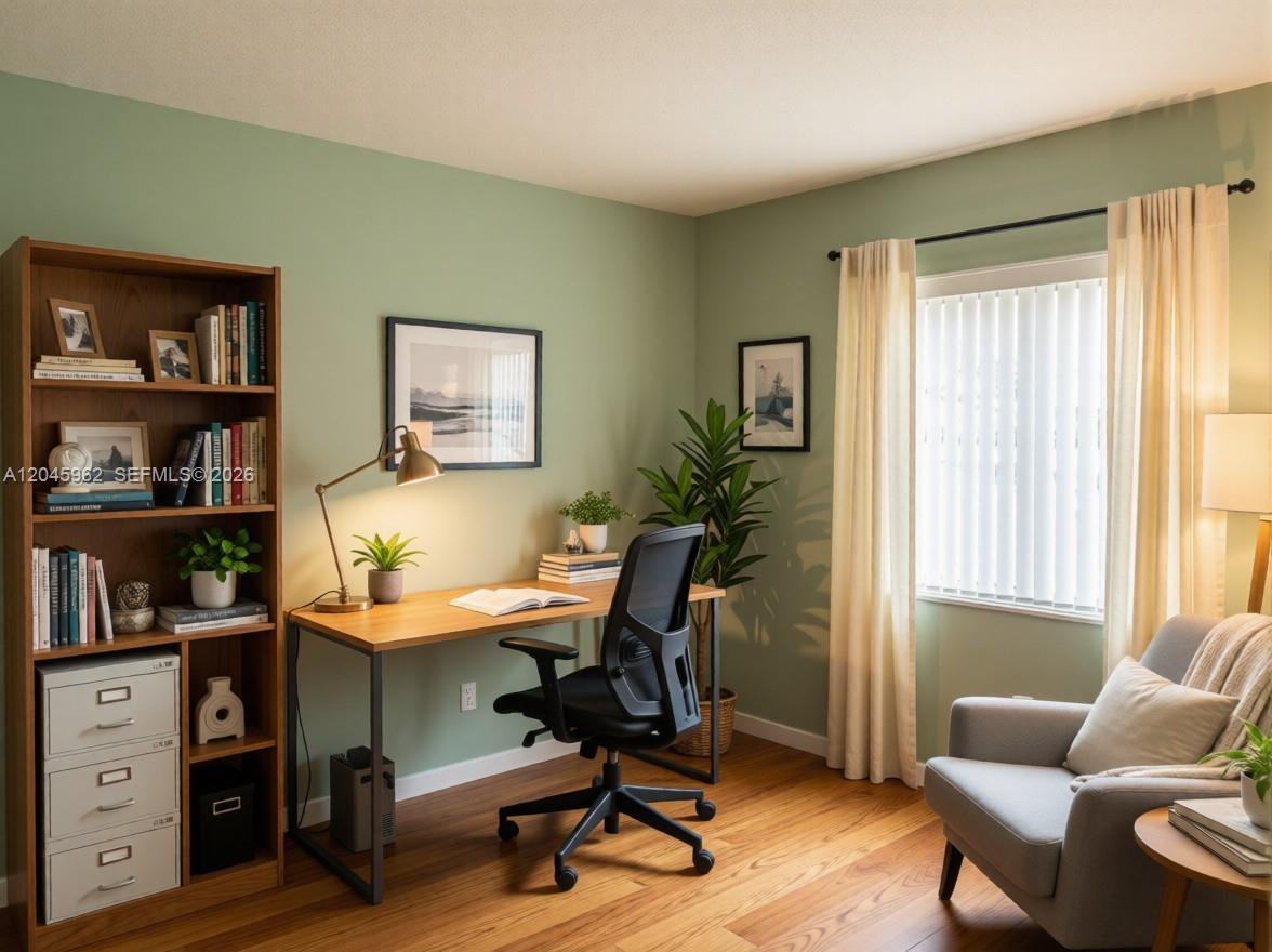 A home office features a wooden desk, a black chair, a bookshelf, and a gray armchair — 1750 W 46th St # 0, Hialeah FL 33012, HIALEAH, FL