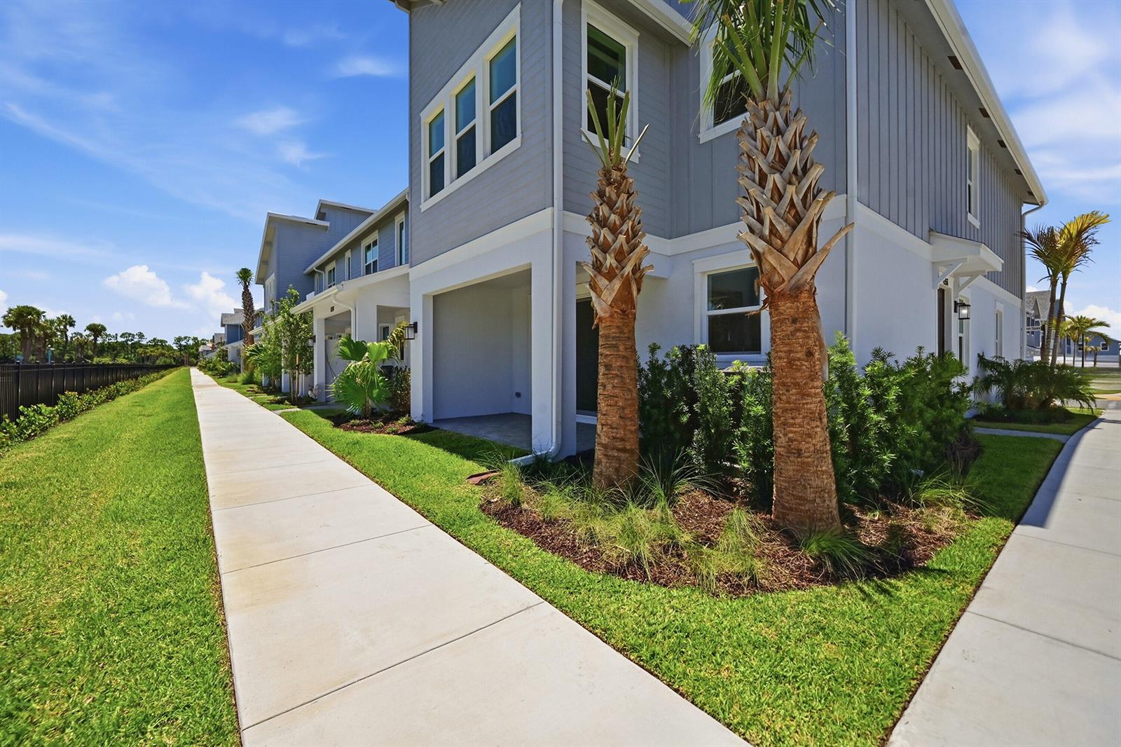 A multi-story grey townhouse exterior with a concrete walkway, palm trees, and landscaped lawn — 4356 Brookgreen Square, Westlake FL 33470, WESTLAKE, FL