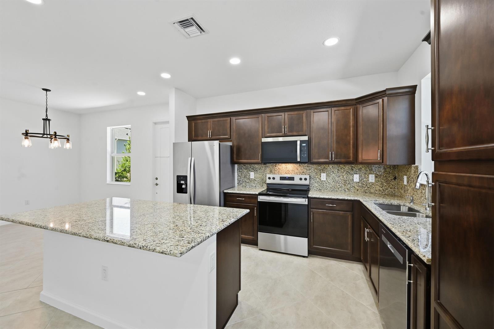 A kitchen features dark wood cabinets, granite countertops, stainless steel appliances, and a central island — 4356 Brookgreen Square, Westlake FL 33470, WESTLAKE, FL