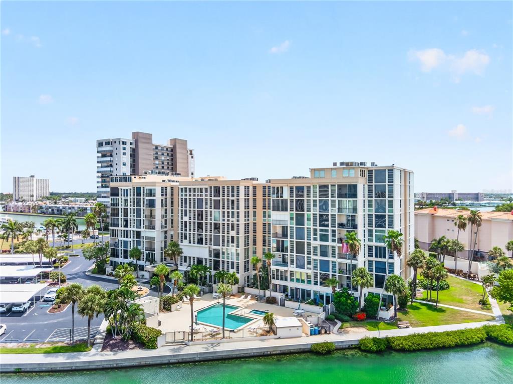An aerial view shows a multi-story apartment complex with a swimming pool and waterfront access — 7400 SUN ISLAND DRIVE S UNIT 203, SOUTH PASADENA, FL