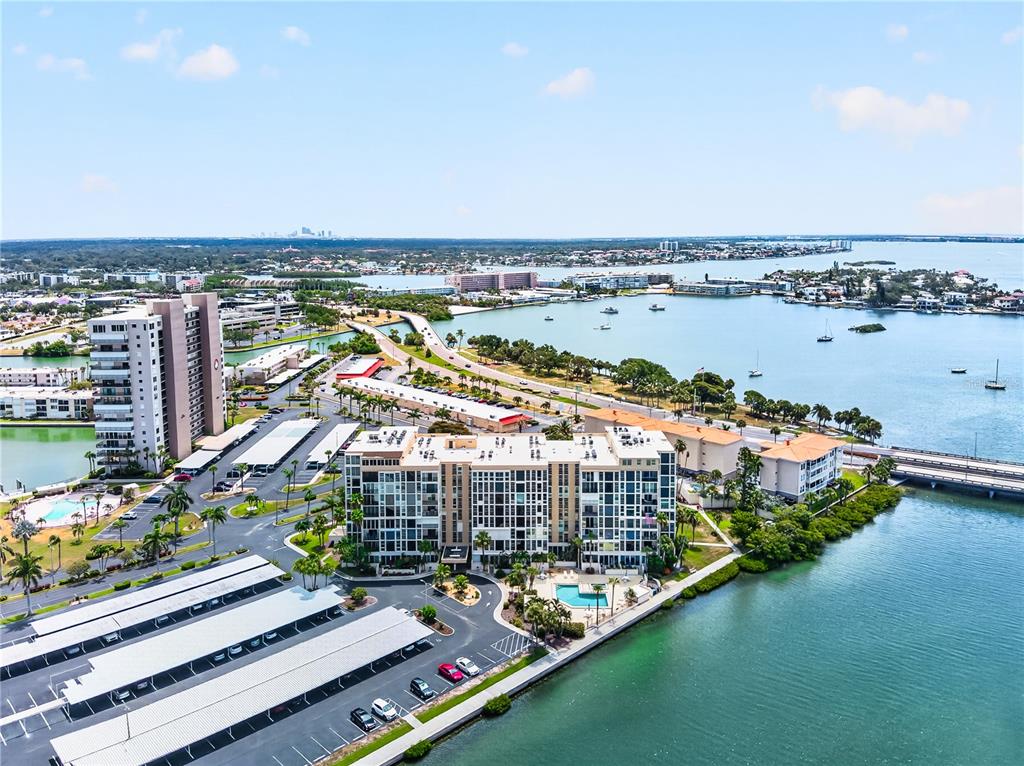 An aerial view shows a multi-story apartment complex with a pool, parking, and waterfront access — 7400 SUN ISLAND DRIVE S UNIT 203, SOUTH PASADENA, FL