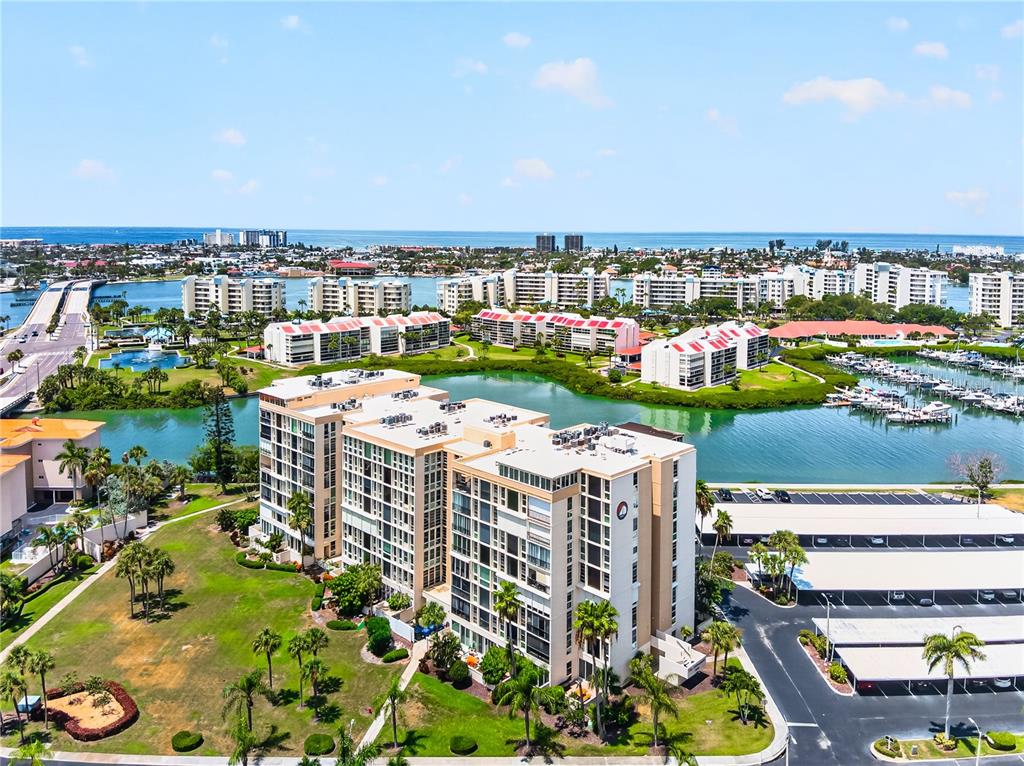 An aerial view shows a multi-story apartment complex near a canal, marina, and the ocean — 7400 SUN ISLAND DRIVE S UNIT 203, SOUTH PASADENA, FL