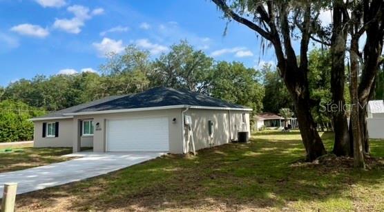 A single-story house with a white garage door and dark shutters sits on a grassy lot — 8640 SE 157 PLACE, SUMMERFIELD, FL