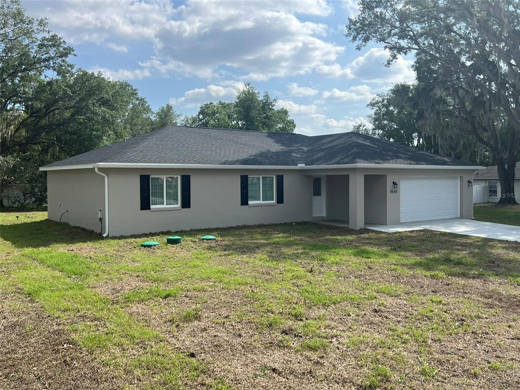 A single-story house with a gray exterior, dark roof, and attached garage sits on grass — 8640 SE 157 PLACE, SUMMERFIELD, FL