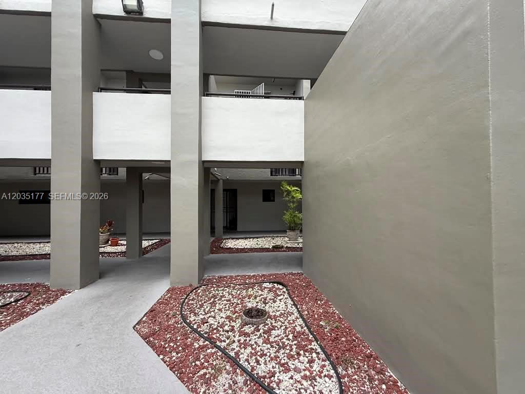 A ground-level view of an apartment building courtyard with red gravel landscaping and walkways — 5 Olive Dr # 12, Hialeah FL 33010, HIALEAH, FL