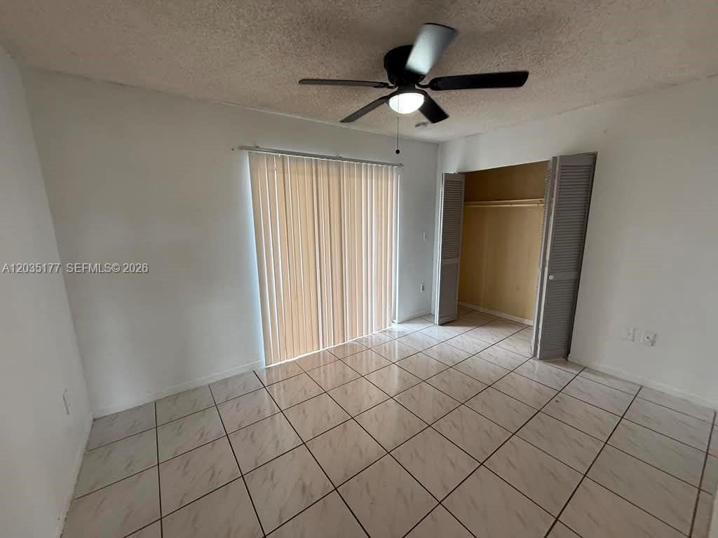 This room features white walls, a ceiling fan, tiled flooring, and a sliding closet — 5 Olive Dr # 12, Hialeah FL 33010, HIALEAH, FL