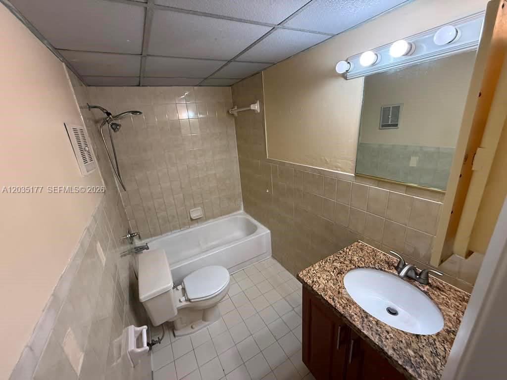 A bathroom features a granite-topped vanity, a tiled shower-tub combination, and a white toilet — 5 Olive Dr # 12, Hialeah FL 33010, HIALEAH, FL