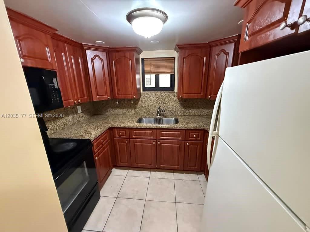 A kitchen features cherry wood cabinets, granite countertops, a double sink, and white appliances — 5 Olive Dr # 12, Hialeah FL 33010, HIALEAH, FL