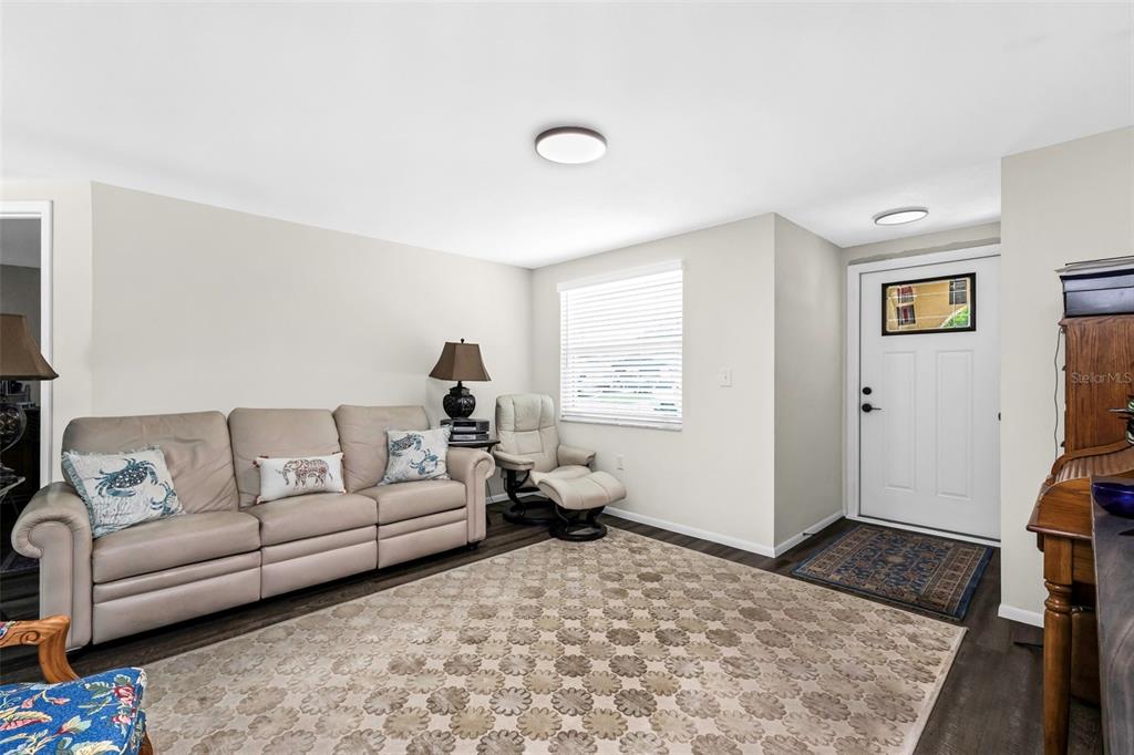 A living room features a beige sofa, a recliner, a patterned rug, and a front door — 1032 ELAINE STREET, VENICE, FL