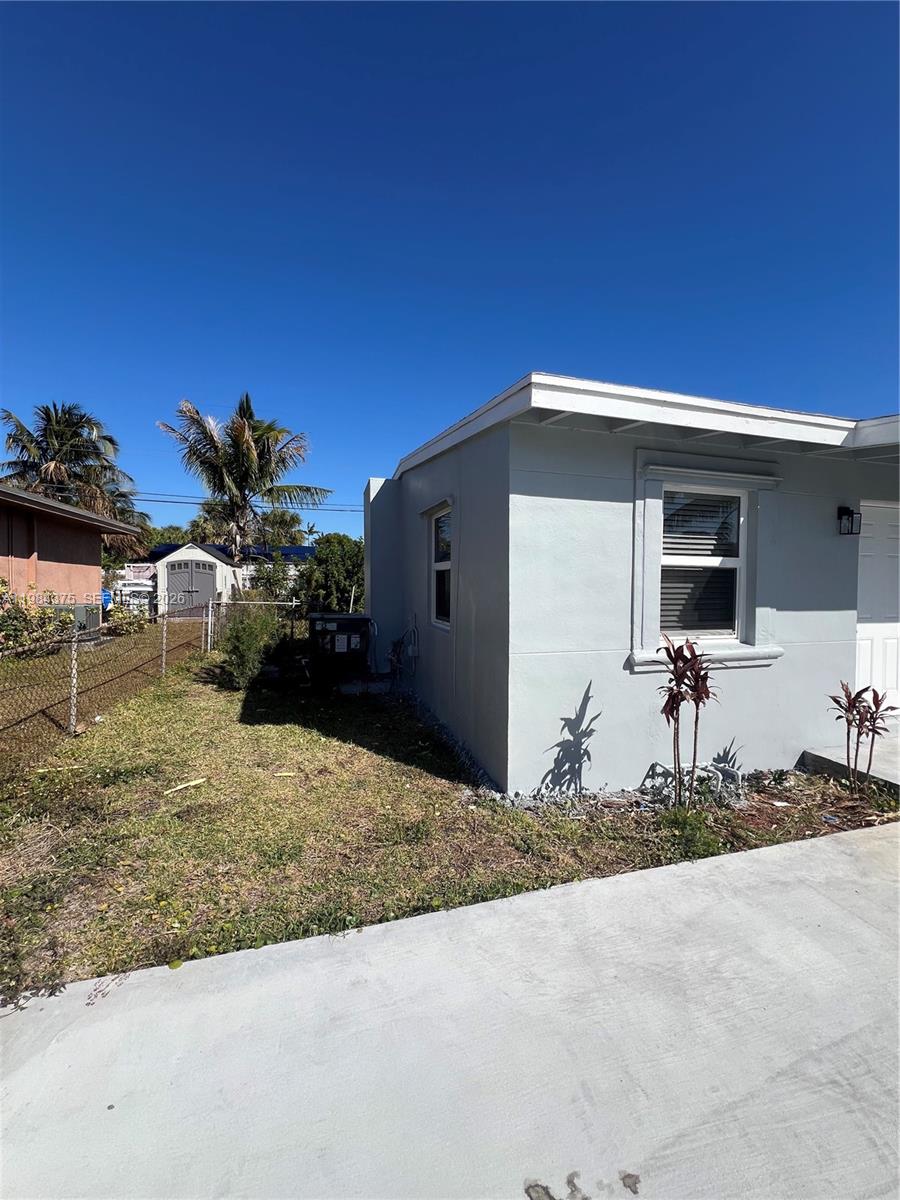 A side view of a light gray house exterior with a small yard and fence — 361 NW 16th St, Pompano Beach FL 33060, POMPANO BEACH, FL