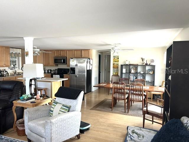 An open-concept living and dining area features light wood flooring, wooden cabinetry, and a kitchen island — 4906 SEA ISLAND AVENUE, SARASOTA, FL