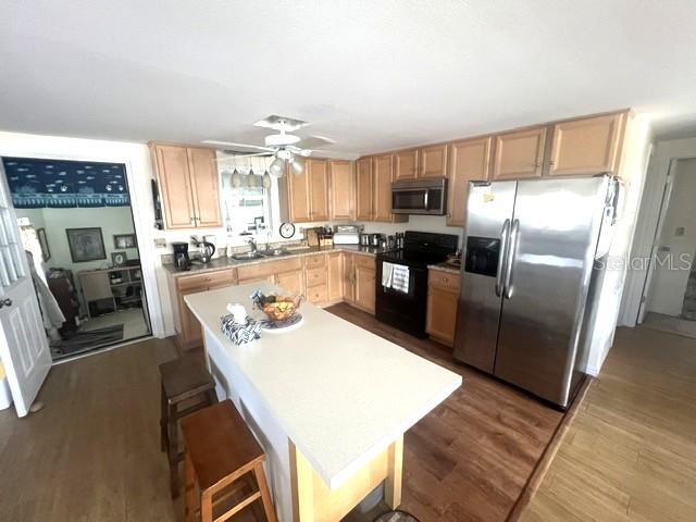 A kitchen features light wood cabinets, a central island, and stainless steel appliances — 4906 SEA ISLAND AVENUE, SARASOTA, FL