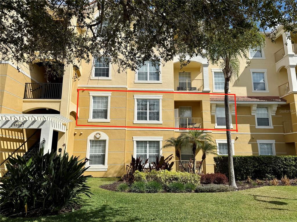 A multi-story yellow apartment building exterior features a red-outlined section highlighting specific windows and balconies — 4802 CAYVIEW AVENUE UNIT 204, ORLANDO, FL