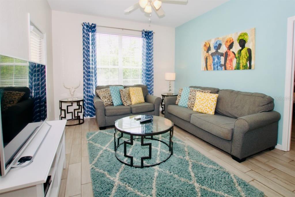 A living room features two gray sofas, a glass coffee table, and a blue rug — 4802 CAYVIEW AVENUE UNIT 204, ORLANDO, FL