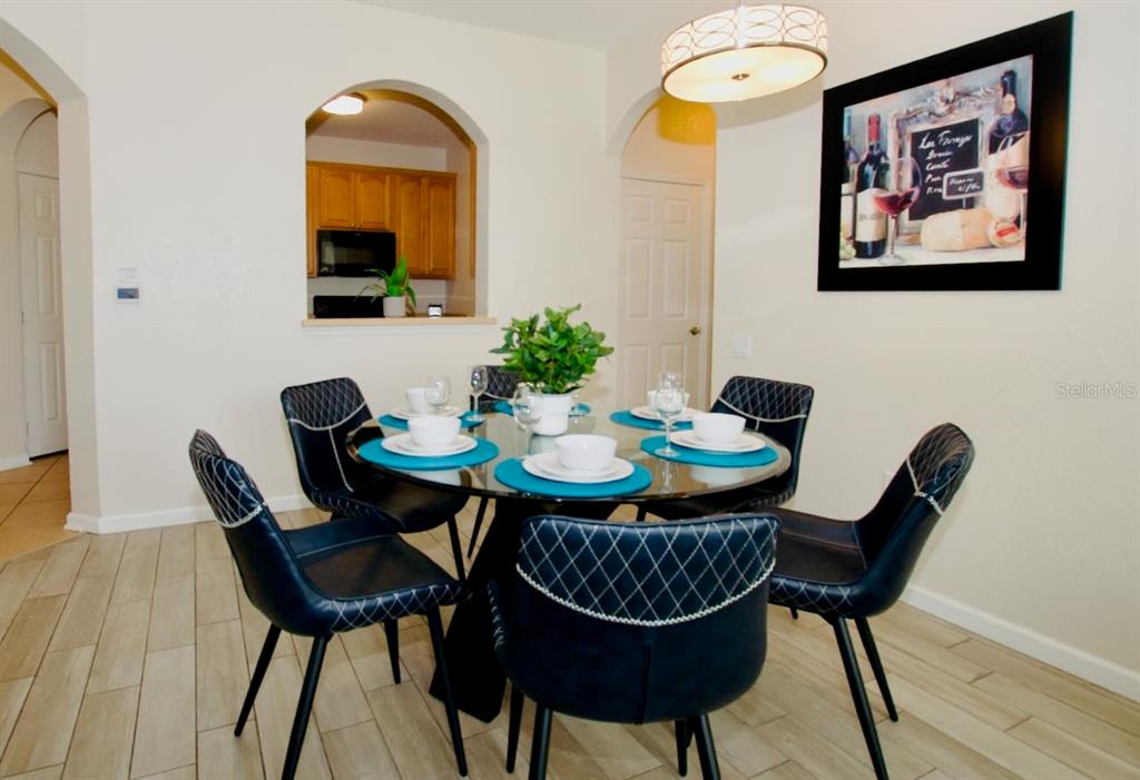 A dining room features a glass-topped table with four dark chairs and a light fixture — 4802 CAYVIEW AVENUE UNIT 204, ORLANDO, FL