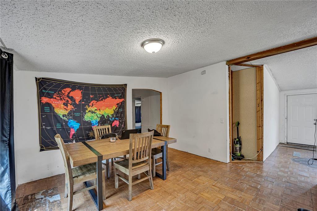 A dining area features a wooden table, a wall-mounted world map, and parquet flooring — 12606 S GRASSY LAKE ROAD, MINNEOLA, FL