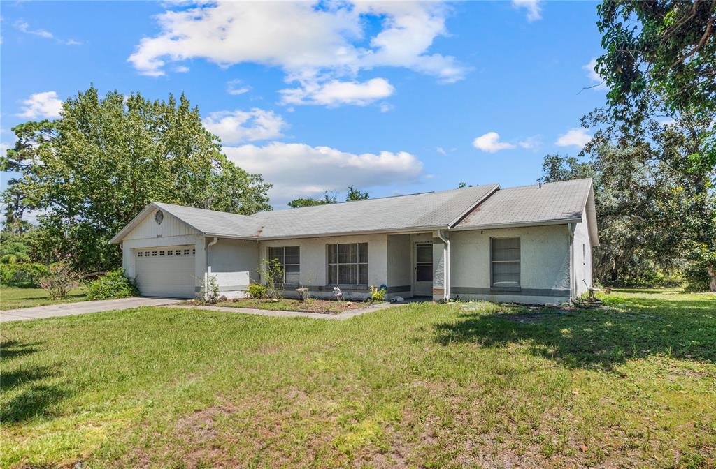 A single-story house with a white stucco exterior, a garage, and a grassy front yard — 5845 LAKE LIZZIE DRIVE, ST CLOUD, FL