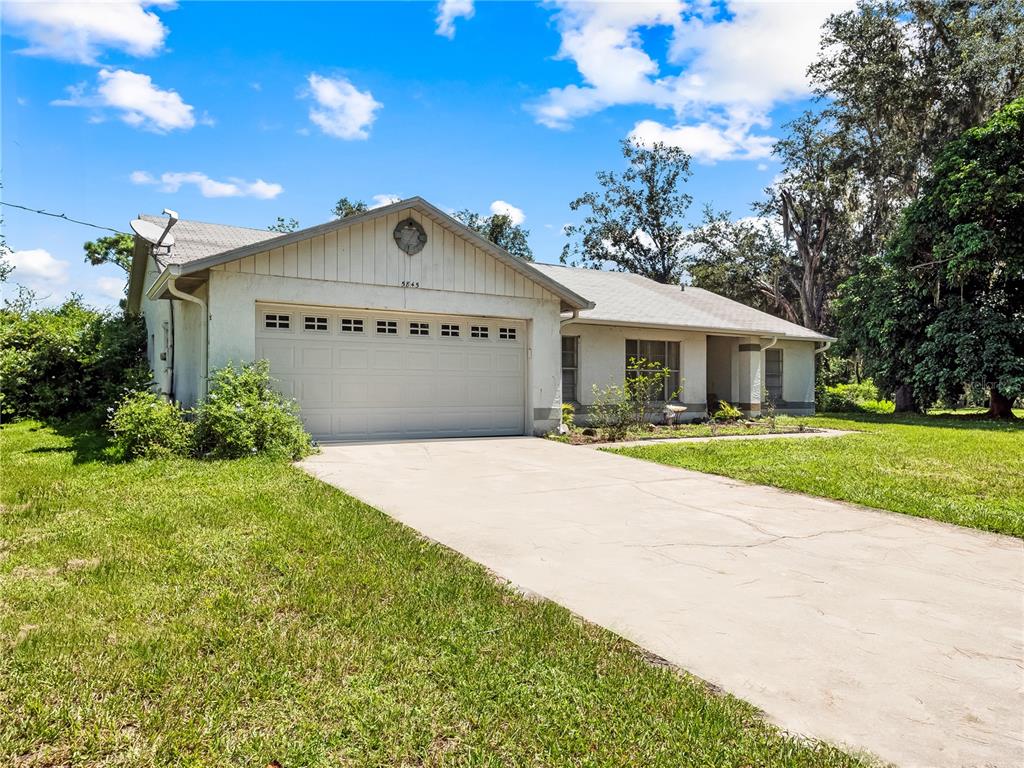 A single-story house with a white stucco exterior, a two-car garage, and a concrete driveway — 5845 LAKE LIZZIE DRIVE, ST CLOUD, FL