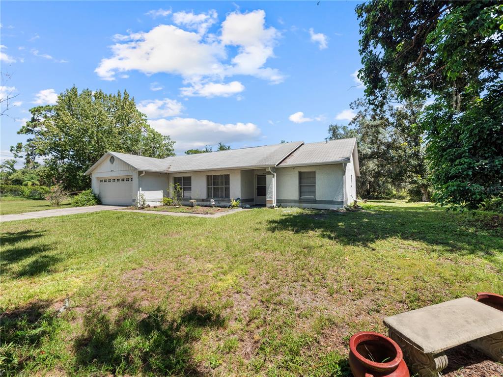 A single-story house with a light-colored stucco exterior and a two-car garage — 5845 LAKE LIZZIE DRIVE, ST CLOUD, FL