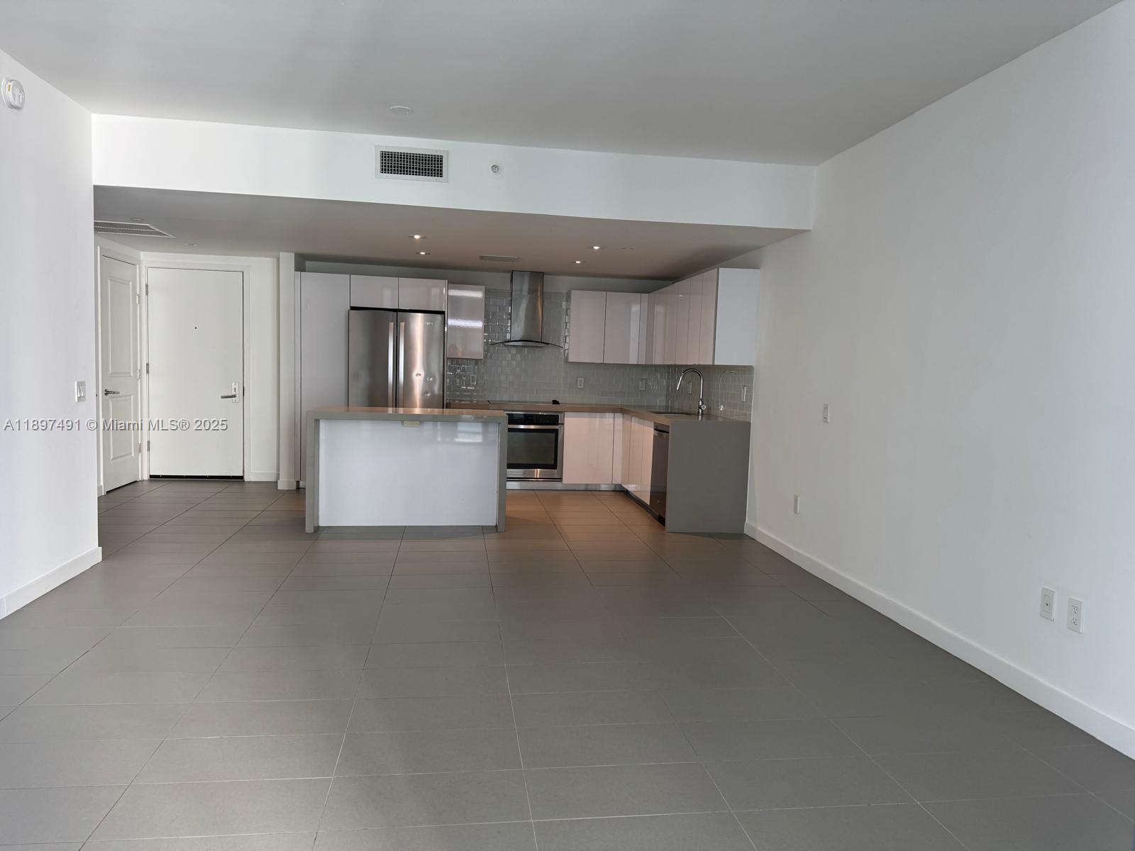 A modern kitchen features white cabinets, stainless steel appliances, and gray tile flooring — 1600 NE 1st Ave # 2217, Miami FL 33132, MIAMI, FL