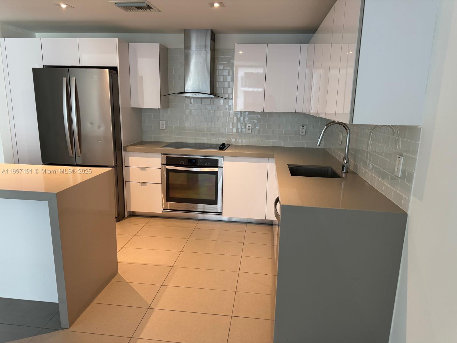A modern kitchen features white cabinets, stainless steel appliances, and gray countertops — 1600 NE 1st Ave # 2217, Miami FL 33132, MIAMI, FL