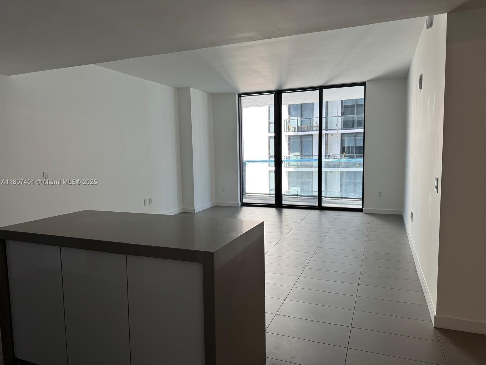 A modern living area features light gray tile flooring, white walls, and a large balcony — 1600 NE 1st Ave # 2217, Miami FL 33132, MIAMI, FL