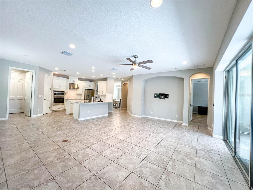 An open-concept living area features tile flooring, a kitchen with white cabinetry, and a ceiling fan — 8033 CLEMENTINE LANE, TAMPA, FL