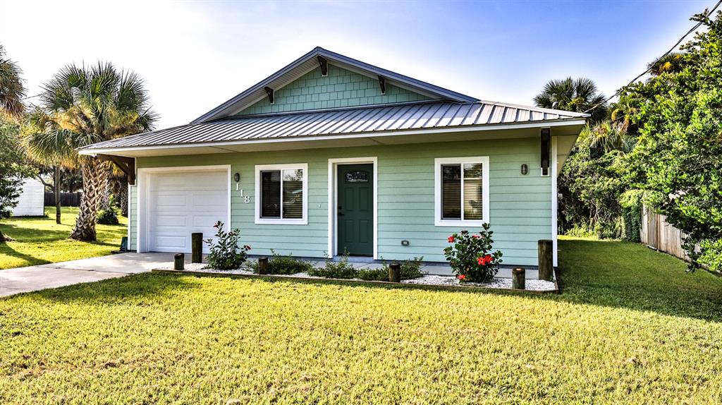 A light green, single-story house with a metal roof, attached garage, and front landscaping — 118 SNYDER STREET, EDGEWATER, FL
