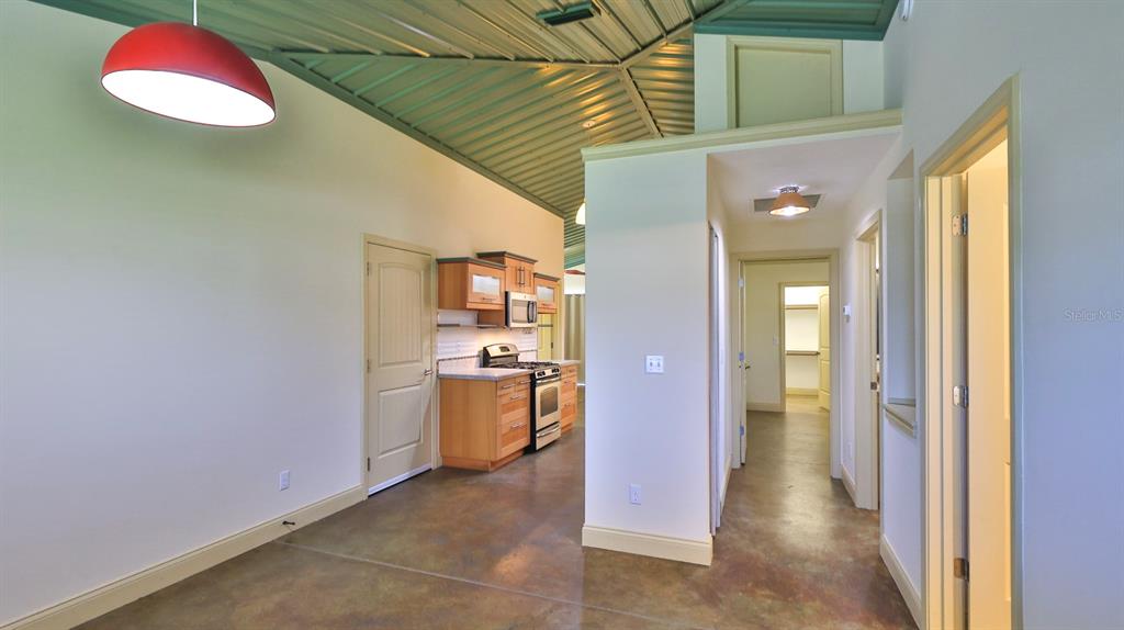 A kitchen with wood cabinets and a metal ceiling opens into a hallway with doors — 118 SNYDER STREET, EDGEWATER, FL