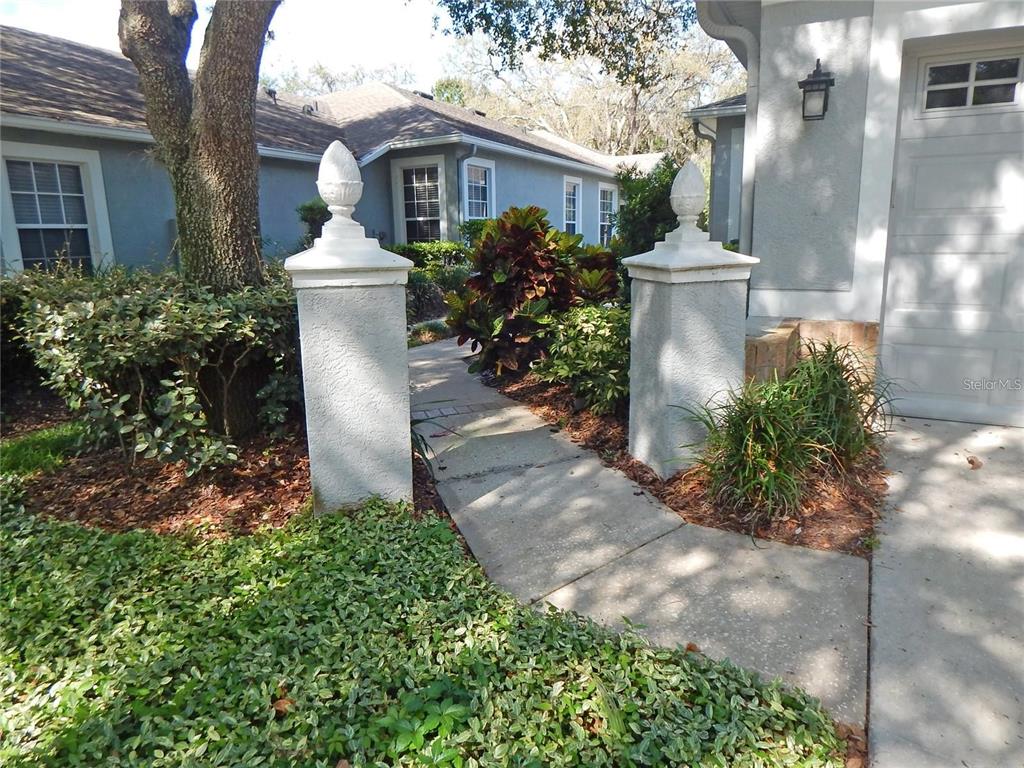 A concrete walkway leads between two stucco pillars toward the entrance of a house — 5925 SANDHILL RIDGE DRIVE, LITHIA, FL