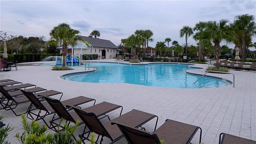 A swimming pool with a splash pad and lounge chairs on a paved deck — 5925 SANDHILL RIDGE DRIVE, LITHIA, FL