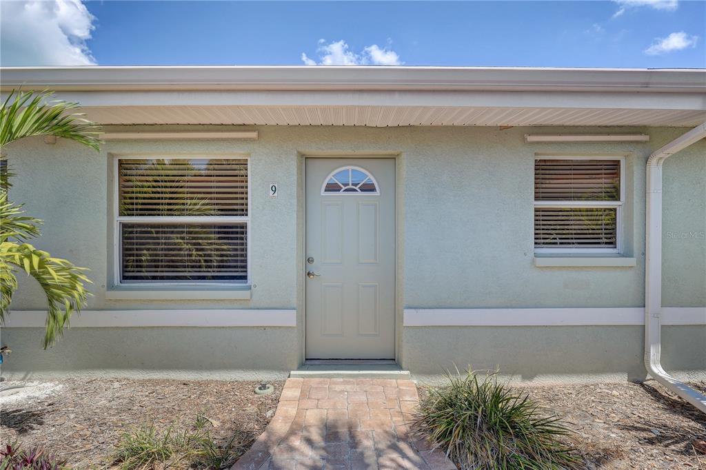 A light green exterior wall features a front door with a small arched window — 9030 BLIND PASS ROAD UNIT C9, ST PETERSBURG, FL