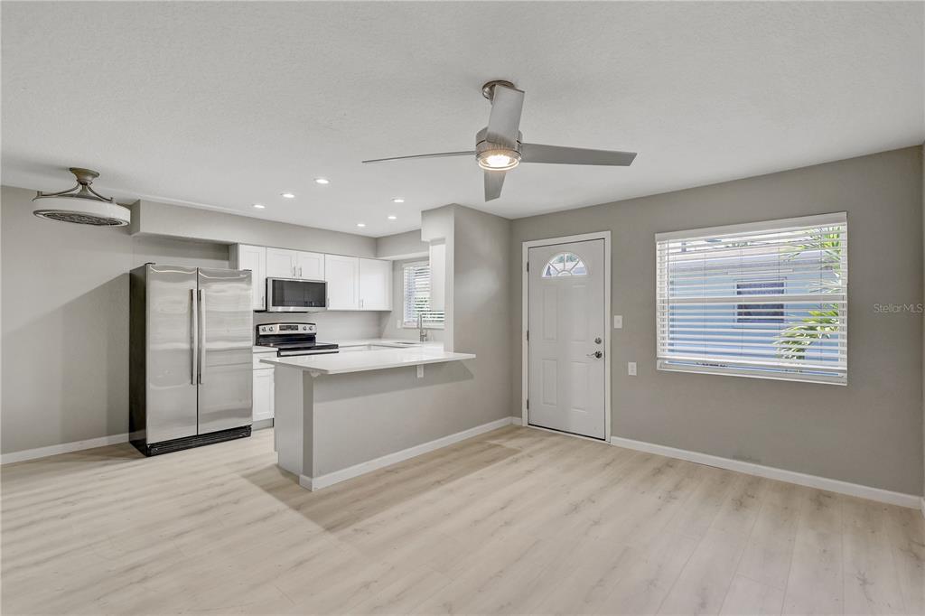 A kitchen with white cabinets and stainless steel appliances opens into a living area — 9030 BLIND PASS ROAD UNIT C9, ST PETERSBURG, FL