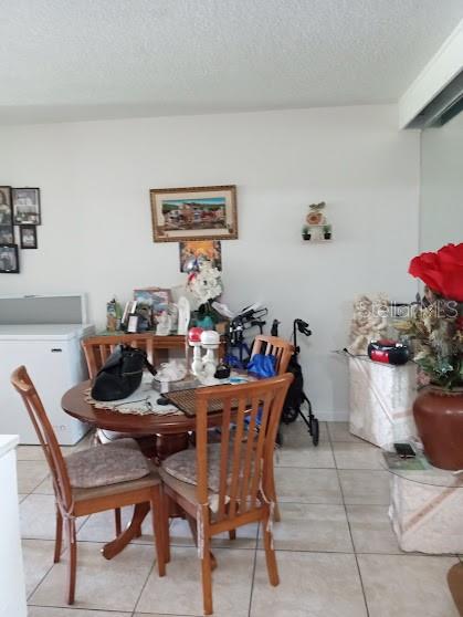 A dining area features a round wooden table with four chairs and tile flooring — 933 W OAK RIDGE ROAD UNIT 933 B, ORLANDO, FL