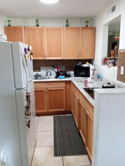 A galley kitchen features light wood cabinets, granite countertops, and a white refrigerator — 933 W OAK RIDGE ROAD UNIT 933 B, ORLANDO, FL