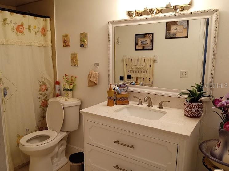 A bathroom features a white vanity, a large mirror, a toilet, and a floral shower curtain — 933 W OAK RIDGE ROAD UNIT 933 B, ORLANDO, FL