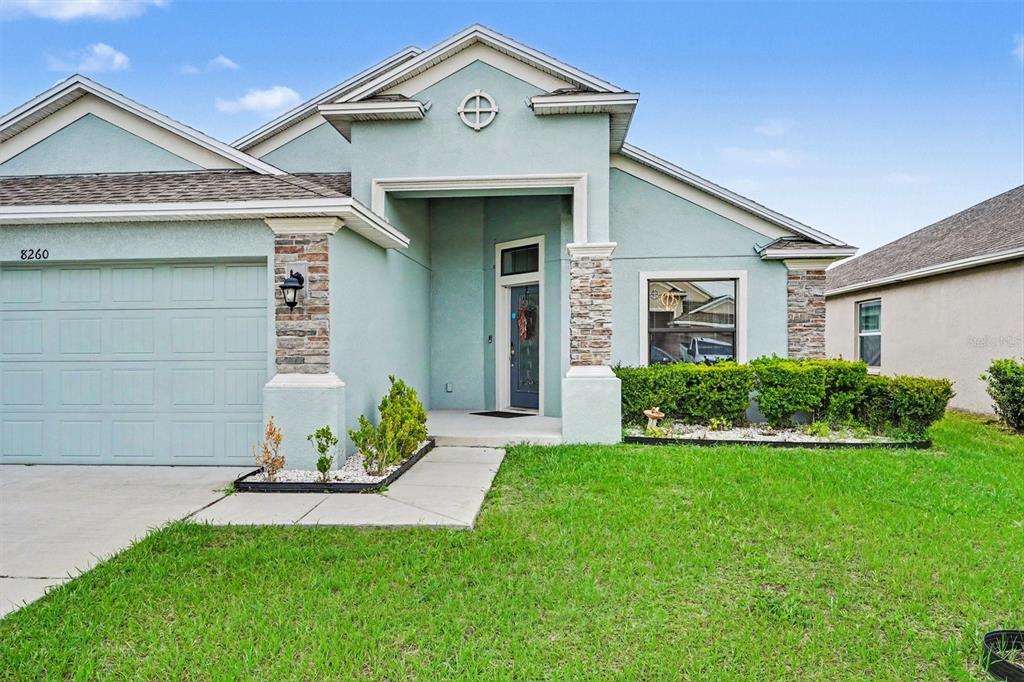 A light blue single-story house features a stone-accented entryway and a two-car garage — 8260 CAMPBELL CROSSING WAY, LAKELAND, FL