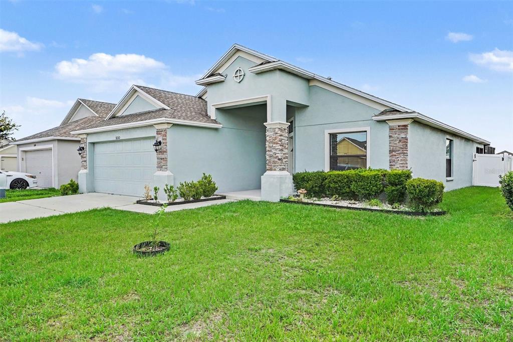A light blue single-story house with a two-car garage and stone-accented columns — 8260 CAMPBELL CROSSING WAY, LAKELAND, FL